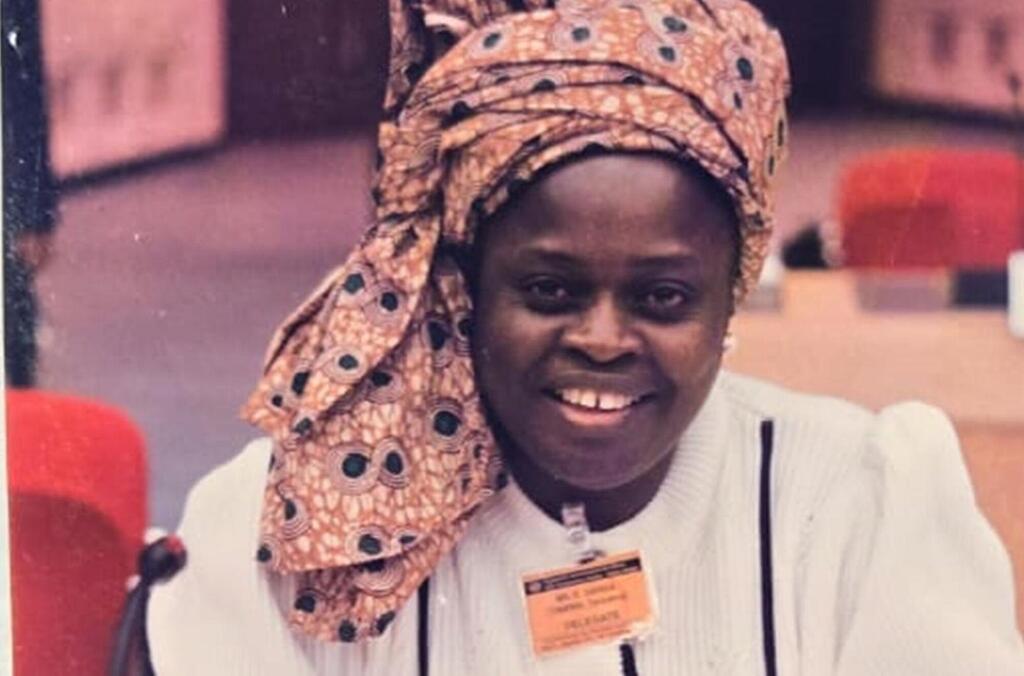 Mwanamke mwenye tabasamu akiwa amevaa kofia ya kichwa iliyo na muundo na beji ya mjumbe katika tukio la Siku ya Redio nchini Kenya.