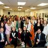 Um grande grupo de profissionais sorridentes, principalmente mulheres, posando para uma foto de grupo em uma conferência ou evento no Brasil.