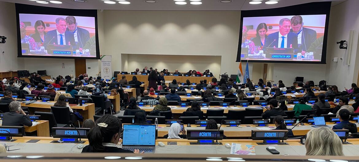 न्यूयॉर्क में संयुक्त राष्ट्र में भारत के स्थायी मिशन में सम्मेलन कक्ष का एक विस्तृत दृश्य, महिला-नेतृत्व विकास और दक्षिण-दक्षिण सहयोगः आईबीएसए फंड से सफलता की कहानियां कार्यक्रम में उपस्थित लोगों से भरा हुआ। सामने बड़ी स्क्रीन एक पैनल चर्चा दिखाती है, और हैशटैग #CSW70 नेमप्लेट और एक फ्रंटग्राउंड डिस्प्ले पर दिखाई देता है।