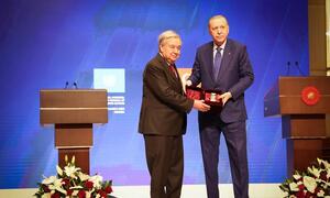 UN Secretary-General António Guterres receives the Atatürk International Peace Prize from Turkish President Recep Tayyip Erdoğan on a stage.