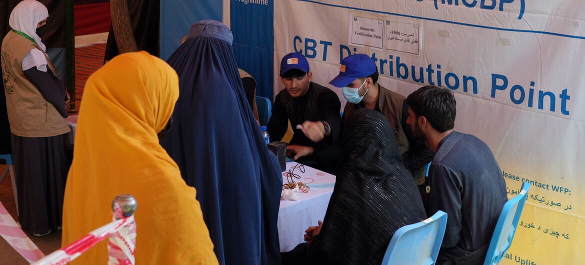افغانستان کے صوبہ کونار کے ضلع کندک سی میں ورلڈ فوڈ پروگرام کے ماں اور بچوں کے فائدے کے پروگرام کی تقسیم کی سائٹ پر ایک ماں کو نقد رقم مل رہی ہے۔