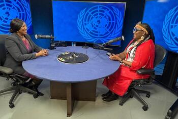 Wanawake wawili wameketi kwenye meza ya mviringo wakiwa na maikrofoni katika studio, na nembo za Umoja wa Mataifa kwenye skrini nyuma yao.
