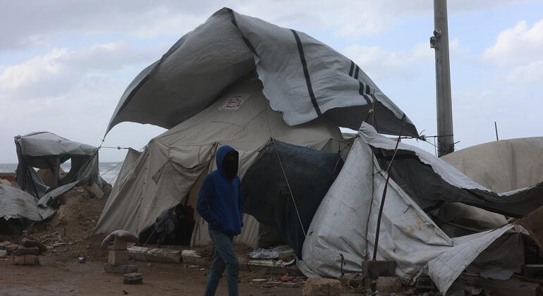 شخص يمشي بجانب خيمة مدمرة في مخيم للاجئين في غزة بعد عاصفة.