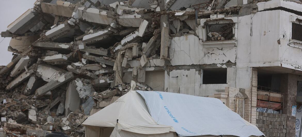 A UNICEF tent stands in front of a destroyed building in Gaza, highlighting the humanitarian crisis and emergency aid efforts in the region.