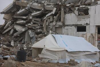A UNICEF tent stands in front of a destroyed building in Gaza, highlighting the humanitarian crisis and emergency aid efforts in the region.
