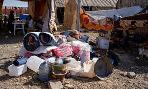 Picha ya hali ya maisha katika kambi ya wakimbizi ya Abu Al Naja nchini Sudan, ikionyesha rundo la misaada ya kibinadamu ikiwa ni pamoja na vifaa vya maji, blanketi, na mifuko ya chakula mbele ya makazi ya muda.