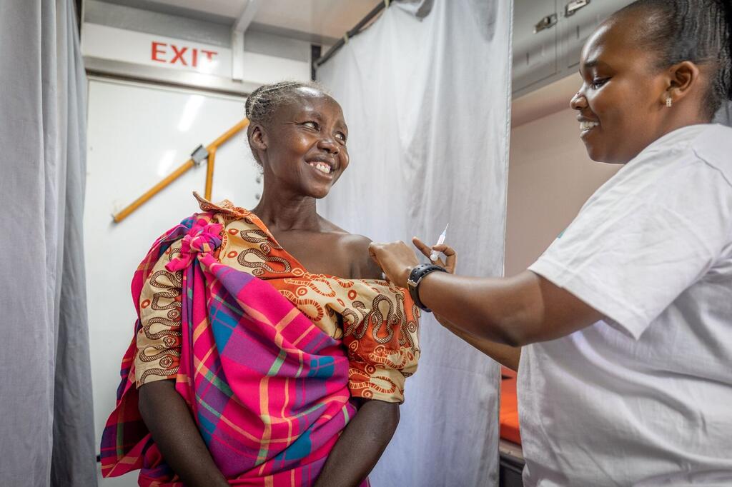 Mwanamke mmoja nchini Kenya anapokea chanjo kutoka kwa mfanyakazi wa afya, akikazia mipango ya Shirika la Afya Ulimwenguni kwa ajili ya afya ya uzazi.