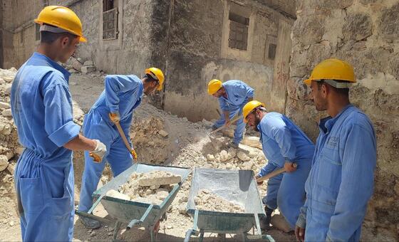 A group of workers remove rubble from a damaged neighbourhood in Syria.