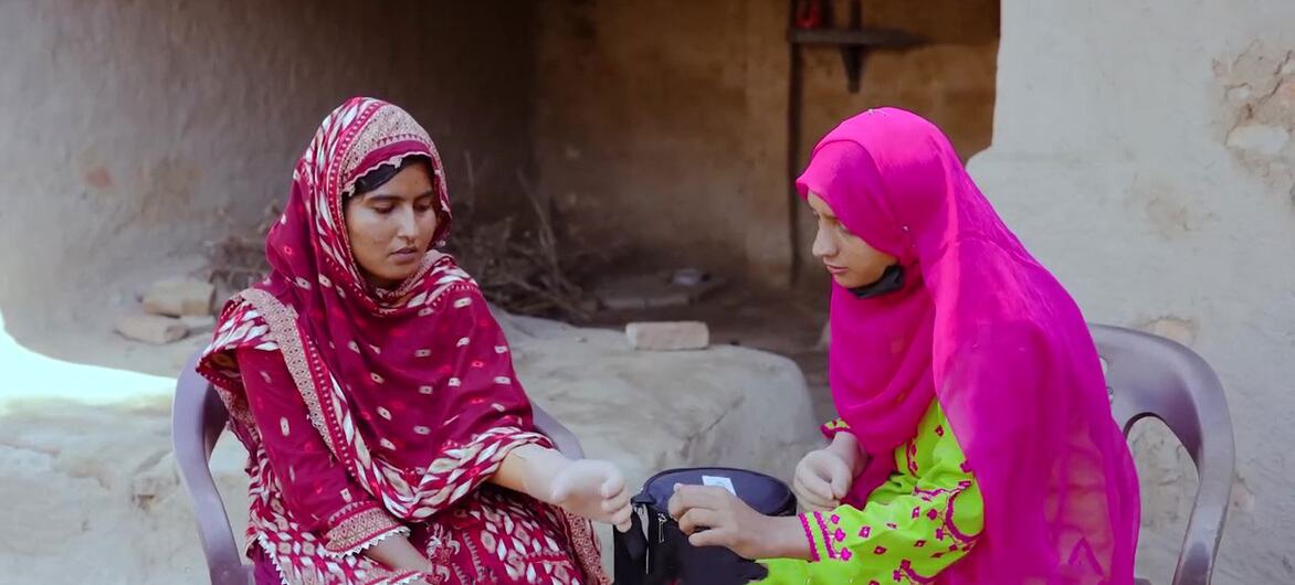 Dos mujeres con ropa tradicional interactúan con un dispositivo protésico en un entorno rural de Pakistán, como parte de una colaboración piloto entre Bioniks y ONU Mujeres.