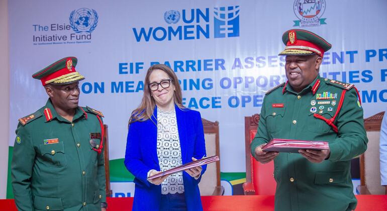 Watu watatu katika tukio: wawili wakiwa wamevaa sare za kijeshi na mmoja akiwa amevaa blazer ya bluu, wakiwa wamesimama mbele ya jukwaa wakiwa na nembo za UN Women na Elsie Initiative Fund.