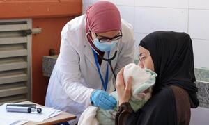 Una trabajadora médica de la Organización Mousawat examina a un bebé recién nacido en manos de su madre en una clínica en el Líbano, proporcionando atención médica a familias desplazadas por el conflicto.