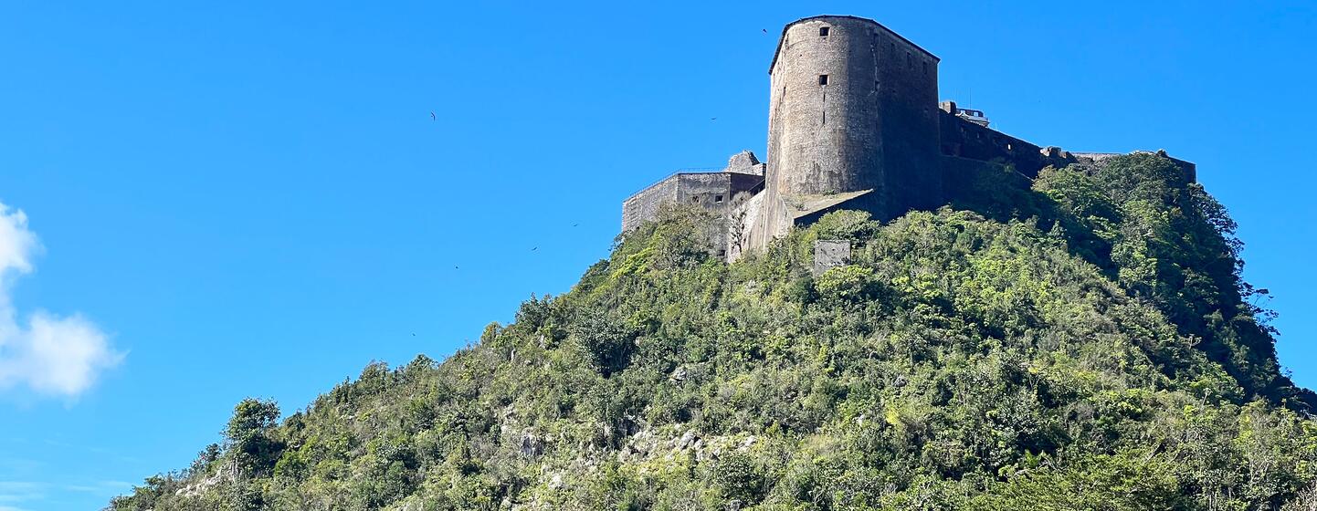 Citadelle Laferrière, une forteresse historique construite après l'indépendance d'Haïti en 1804, est perchée au sommet d'une montagne verdoyante sous un ciel bleu clair.