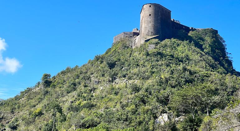 Citadelle Laferrière, une forteresse historique construite après l'indépendance d'Haïti en 1804, est perchée au sommet d'une montagne verdoyante sous un ciel bleu clair.