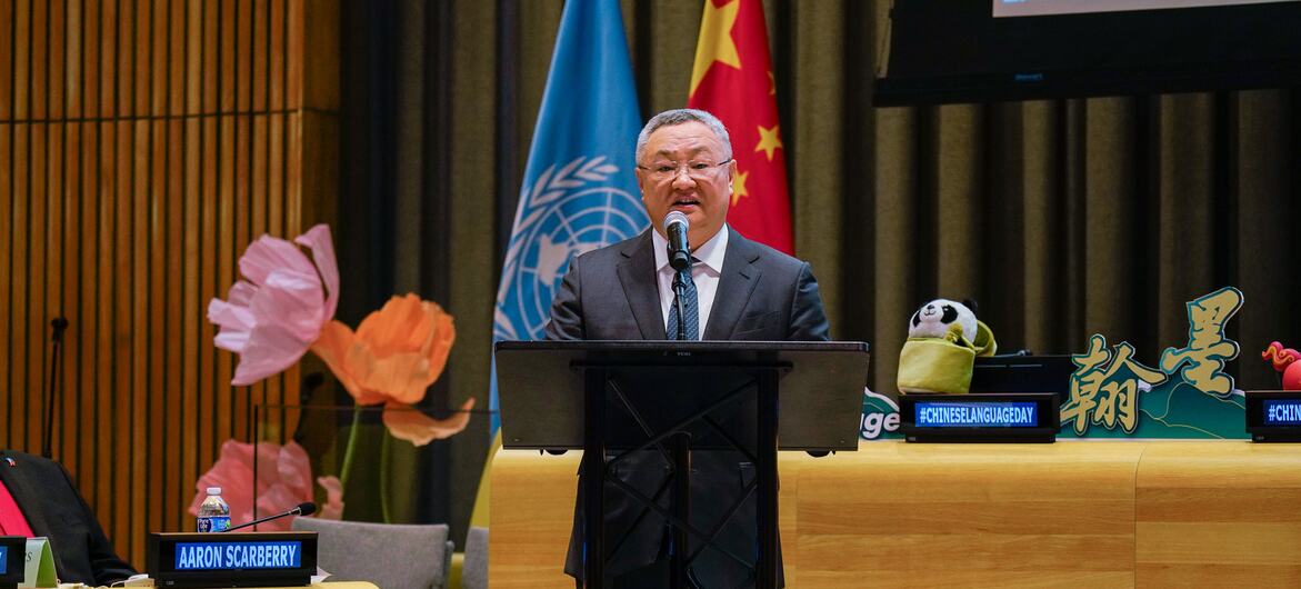 亚伦·斯卡伯里在中国语言日活动期间于讲台发言，身后悬挂着联合国和中国国旗。