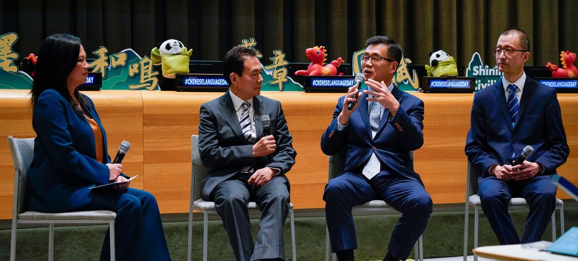 在中国语言日活动的舞台上，四人就座参加小组讨论。一位身着蓝色西装的女士担任主持人，三位身着西装的男士参与讨论，手中均持有麦克风。