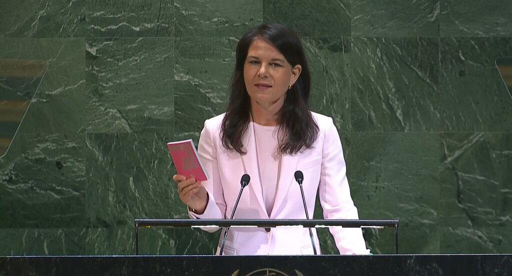 Annalena Baerbock, présidente de la 80e session de l'Assemblée générale des Nations Unies, en train de parler sur le podium en tenant une brochure rouge.
