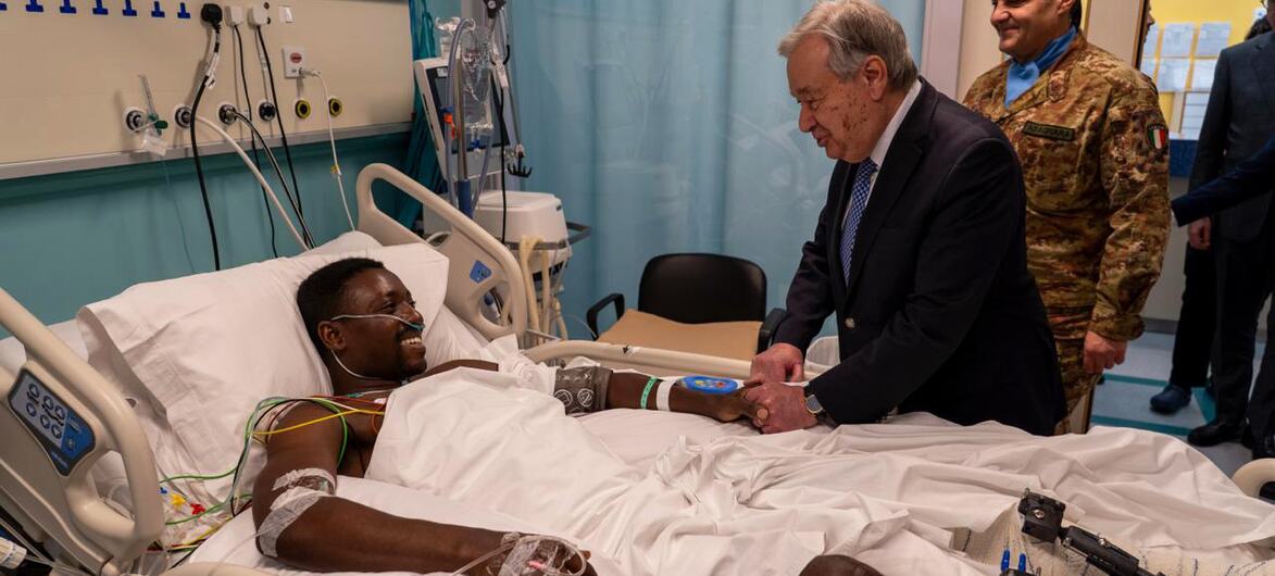 UN Secretary-General Ant&oacute;nio Guterres shaking hands with a Lebanese Army soldier recovering in a hospital bed in Lebanon, with another soldier standing by.