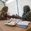 Amina, une sage-femme déplacée d'Al Fasher, mesure la tension artérielle d'une femme enceinte dans un centre de santé soutenu par l'UNICEF à Tawila, dans le Darfour du Nord, au Soudan. L'image montre Amina utilisant un sphygmomanomètre sur une femme assise portant un foulard à motif léopard, avec du matériel médical sur la table.