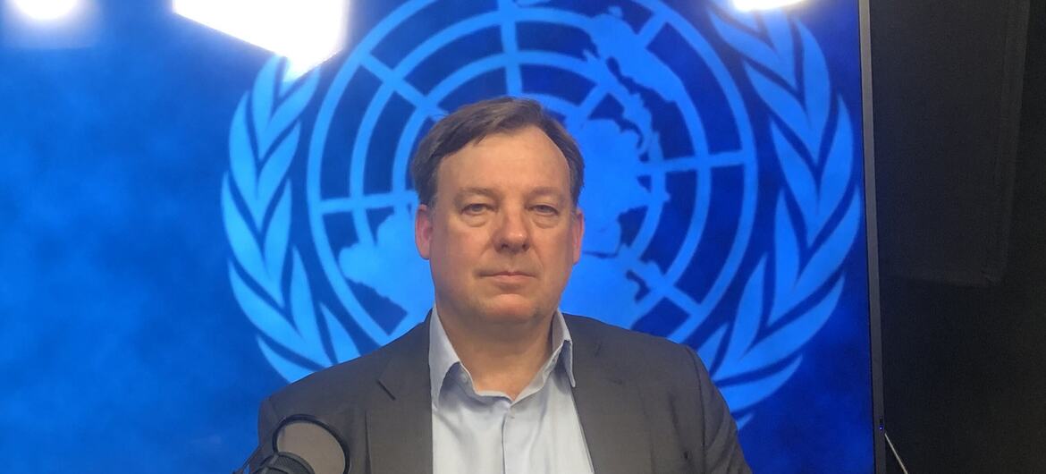 Майкл Херрманн, представитель ЮНФПА, говорит в микрофон перед логотипом ЮНФПА.