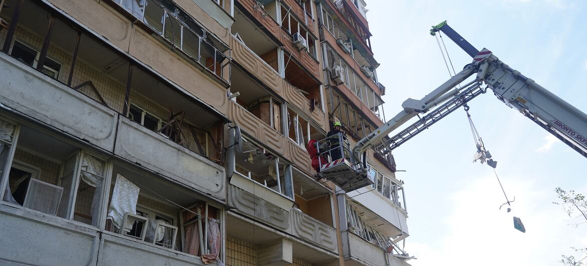 Un bombero en la cesta de una grúa elevadora trabaja en la fachada de un edificio residencial dañado en Kiev, Ucrania, tras un ataque con dron y misil.