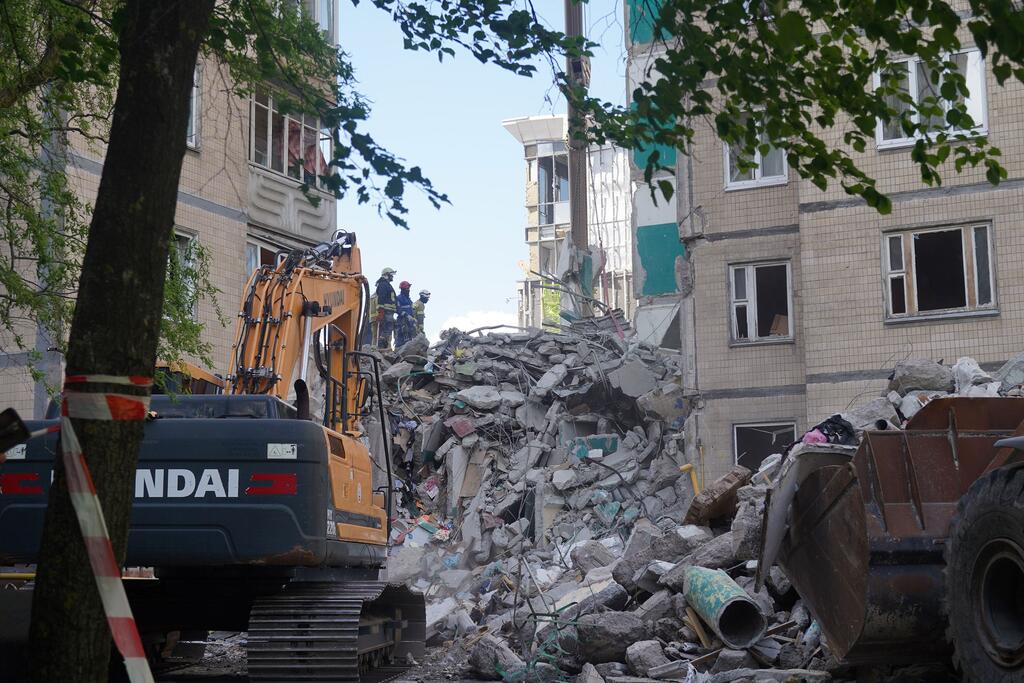 Waokoaji na mchimbaji kwenye jengo la makazi lililoharibiwa huko Kyiv kufuatia shambulio la makombora na droni za Urusi.