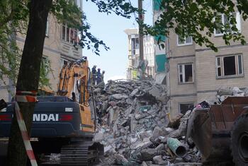 Des sauveteurs et une pelleteuse devant un immeuble résidentiel endommagé à Kiev à la suite d'une attaque de missiles et de drones russes.