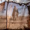 A silhouette of a woman standing inside a makeshift tent in a refugee camp in Tawila, North Darfur, Sudan.