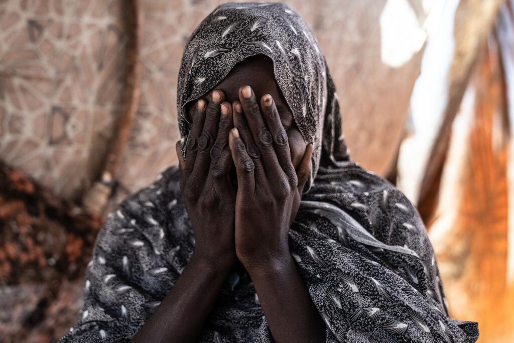 Shadia, une survivante de violences sexuelles, se couvre le visage avec ses mains à l'intérieur de sa tente dans un camp de déplacés à Tawila, au Darfour du Nord.