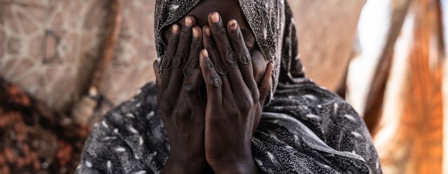 Shadia, une survivante de violences sexuelles, se couvre le visage avec ses mains à l'intérieur de sa tente dans un camp de déplacés à Tawila, au Darfour du Nord.