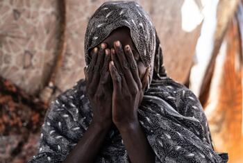 Shadia, a survivor of sexual violence, covers her face with her hands inside her tent in a displacement camp in Tawila, North Darfur.