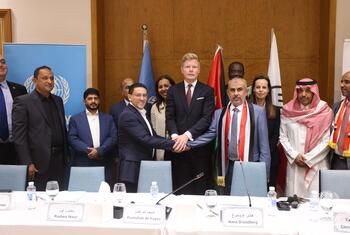 رؤساء الوفود من حكومة اليمن (على اليمين) والحوثيين (على اليسار) يتصافحون بعد توقيع اتفاق لإطلاق سراح أكثر من 1600 معتقل مرتبط بالنزاع تحت رعاية المبعوث الخاص للأمم المتحدة إلى اليمن (في الوسط).