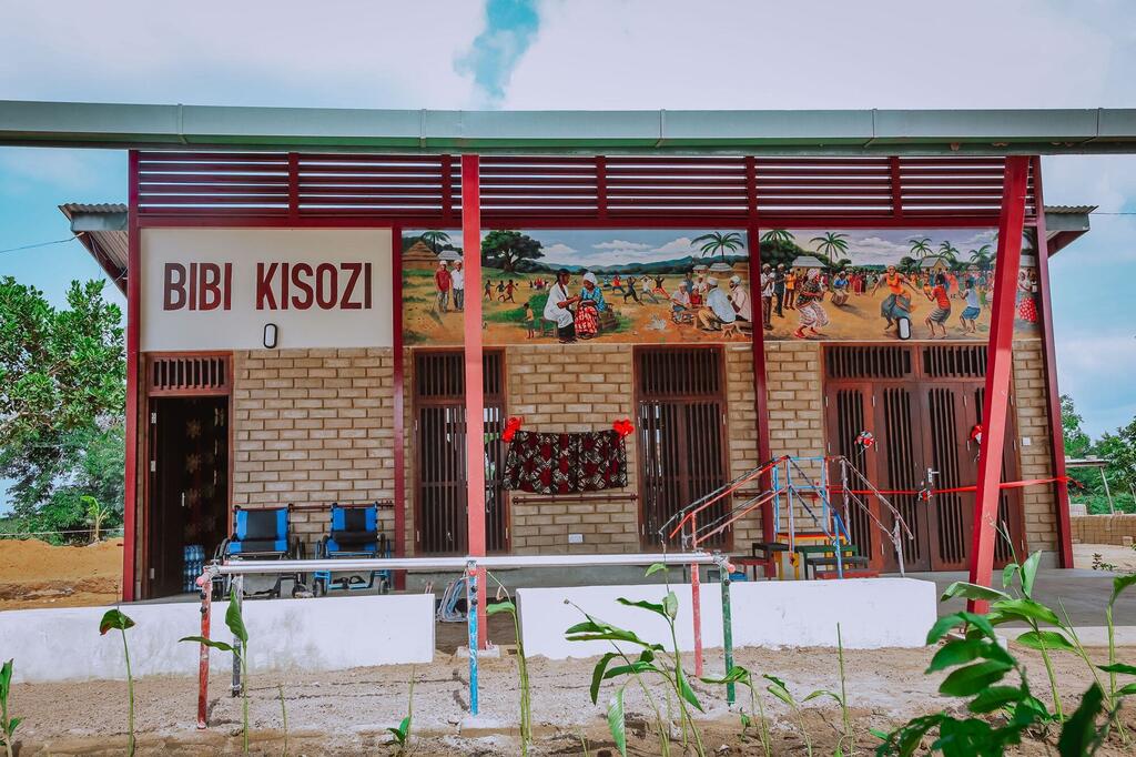 Jengo jipya lenye picha ya ukuta inayowakilisha wanawake na watoto nchini Tanzania, na alama inayosema "Bibi Kisozi".