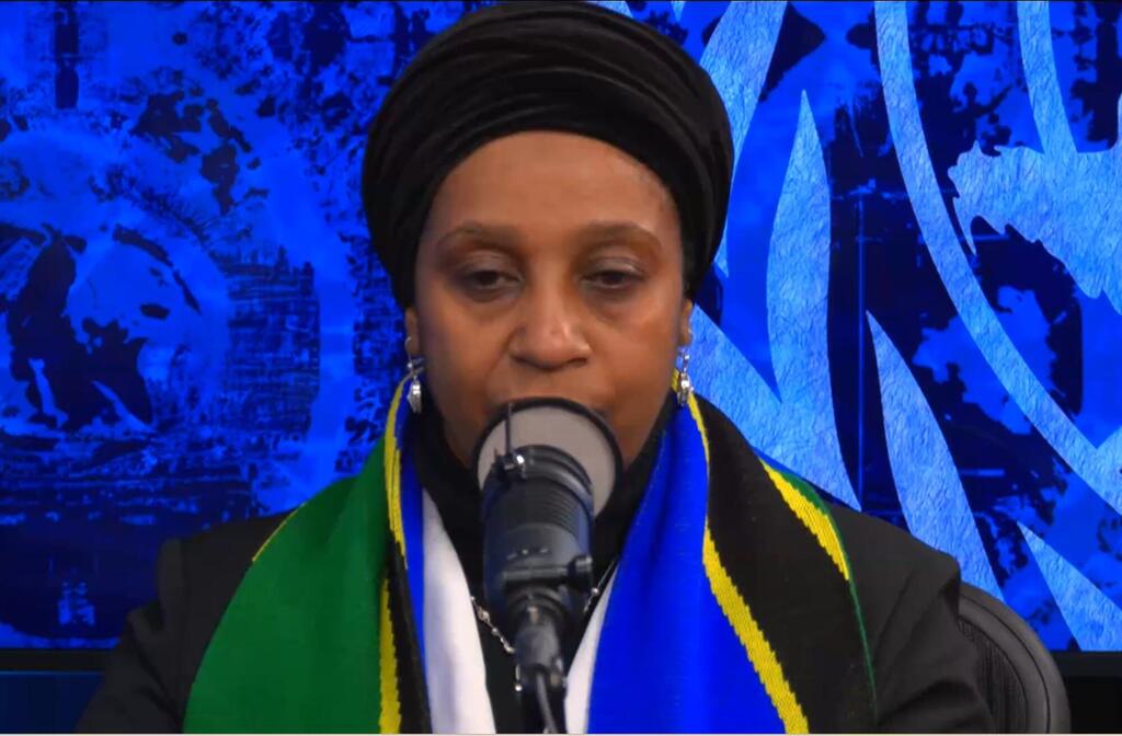 Mwanamke aliyevaa hijabu na mshipi wenye rangi za bendera ya Tanzania akizungumza kwenye kipaza sauti katika tukio la Umoja wa Mataifa.