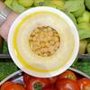 Un tazón de garbanzos en aceite de oliva, rodeado de verduras frescas como tomates y manzanas verdes.