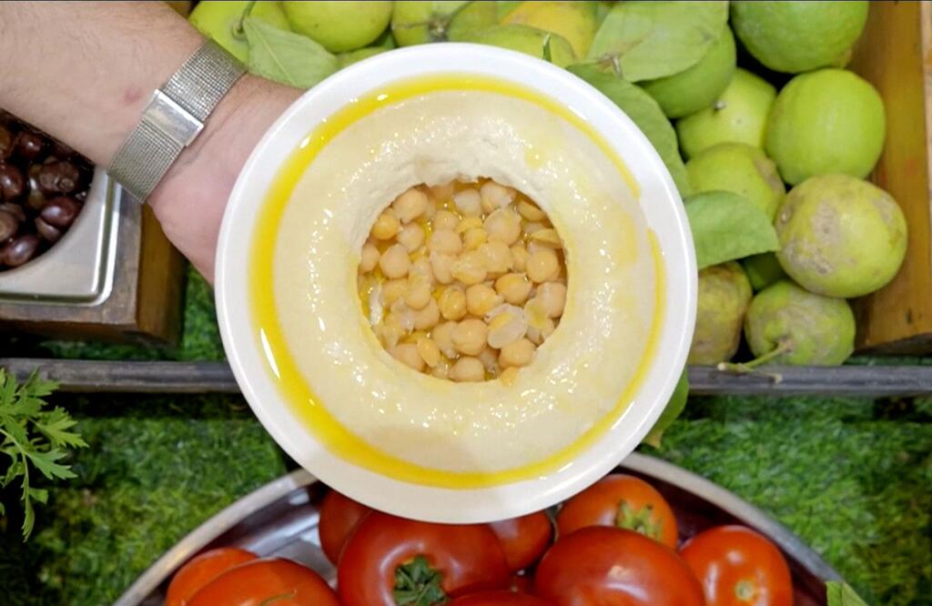 Sahani ya chickpeas katika mafuta ya zeituni, kuzungukwa na mboga safi kama nyanya na apples kijani.