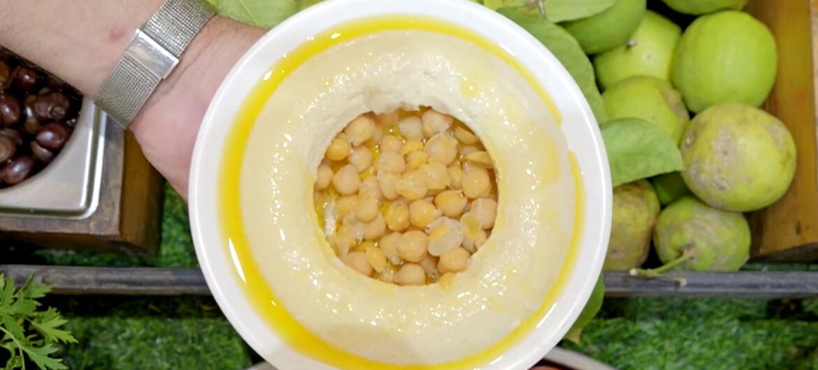 जैतून के तेल में चिकन के एक कटोरे, टमाटर और हरे सेब जैसे ताजे सब्जियों से घिरा हुआ।