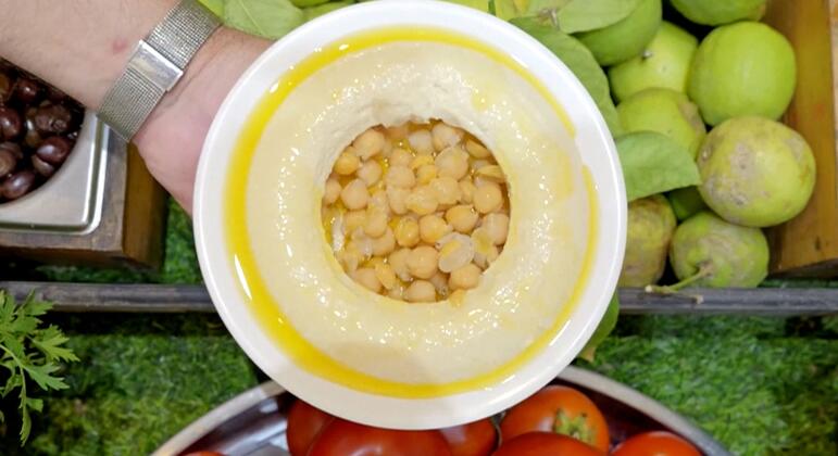 जैतून के तेल में चिकन के एक कटोरे, टमाटर और हरे सेब जैसे ताजे सब्जियों से घिरा हुआ।