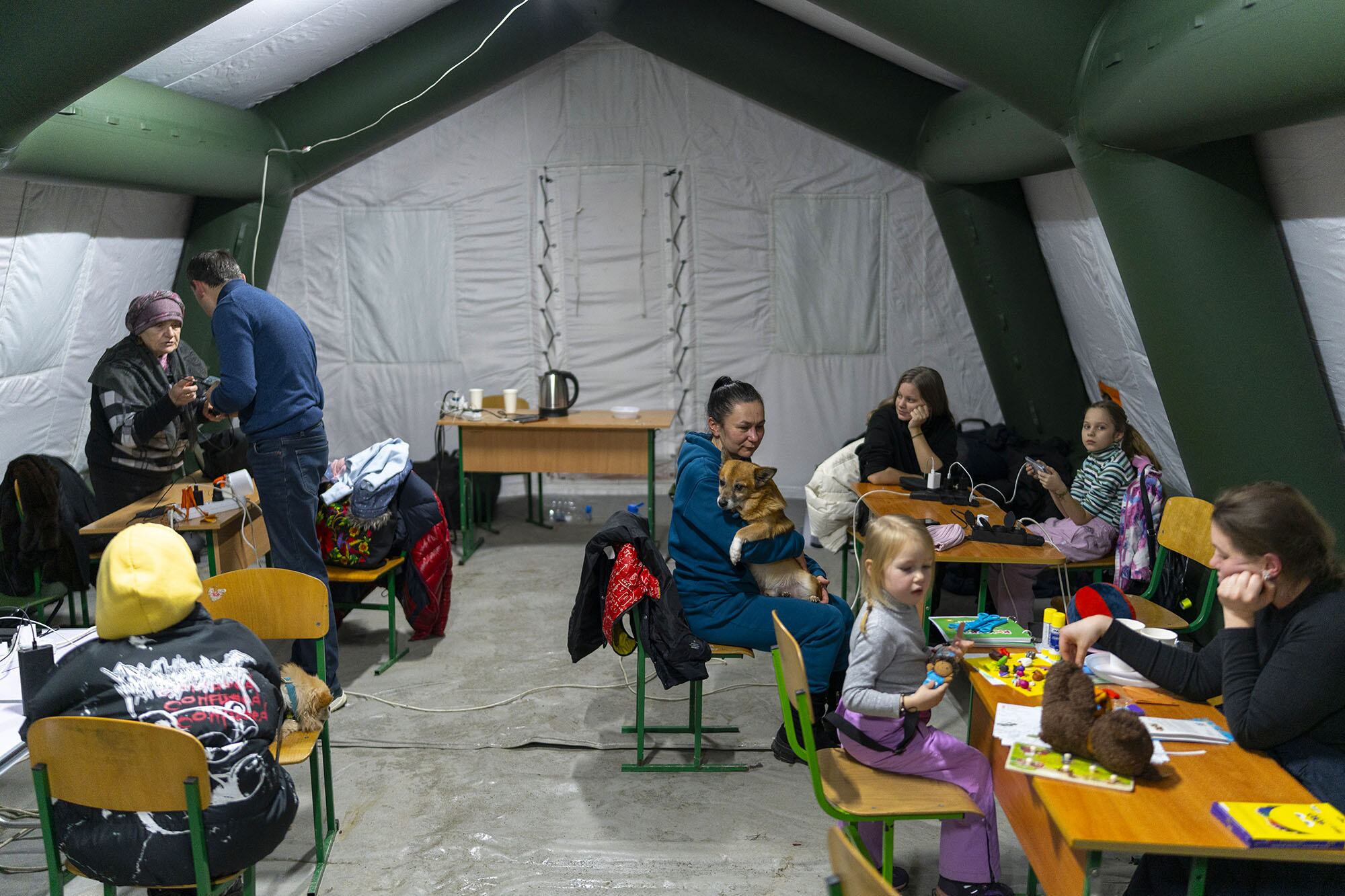Les familles avec des enfants se rassemblent à l'intérieur d'une tente mobile "Point of Invincibility" chauffée à Kiev, en Ukraine, pendant une panne d'électricité d'hiver. Les parents chargent des appareils et préparent des boissons chaudes pendant que les enfants jouent avec des jouets et des modèles d'argile, soutenus par les kits de premiers secours psychologiques de l'UNICEF et les services psychosociaux.