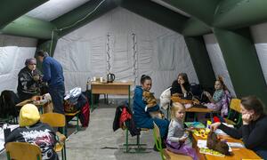 Las familias con niños se reúnen dentro de una tienda móvil "Point of Invincibility" en Kiev, Ucrania, durante un corte de energía de invierno. Los padres cargan los dispositivos y preparan bebidas calientes mientras los niños juegan con juguetes y modelan arcilla, apoyados por los kits de primeros auxilios psicológicos de UNICEF y los servicios psicosociales.