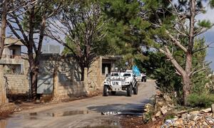 Un vehículo blindado de patrulla de la UNIFIL con soldados con cascos azules conduce por un camino de tierra en una zona boscosa del Líbano.
