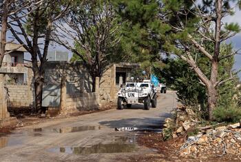 مركبة دورية مدرعة من قوات اليونيفيل مع جنود يرتدون خوذة زرقاء يقودون على طول طريق تراب في منطقة غابات في لبنان.