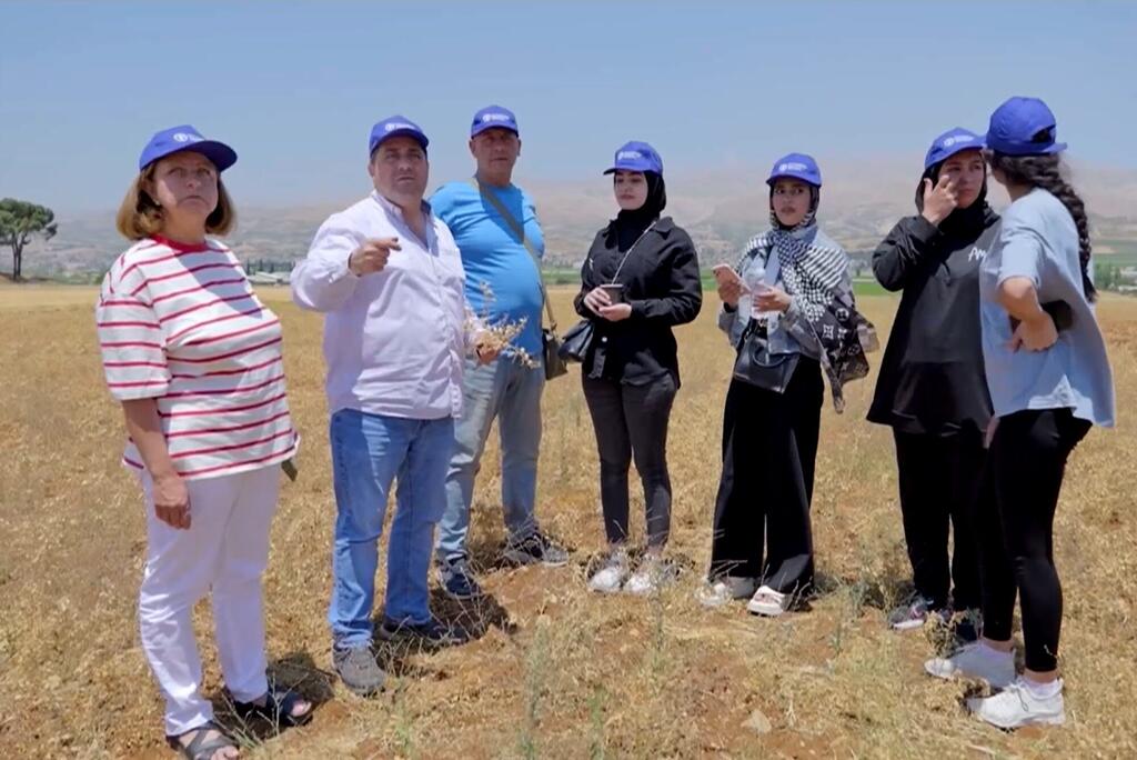 Kikundi cha watu waliovaa kofia za FAO za bluu wamesimama katika shamba kavu nchini Lebanon, wakifanya ziara ya shamba la kilimo iliyozingatia uzalishaji wa chickpeas na protini.