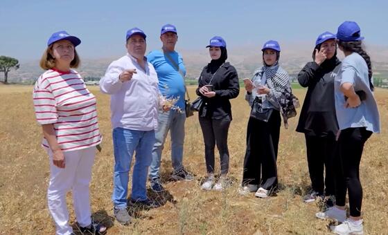 Kikundi cha watu waliovaa kofia za FAO za bluu wamesimama katika shamba kavu nchini Lebanon, wakifanya ziara ya shamba la kilimo iliyozingatia uzalishaji wa chickpeas na protini.