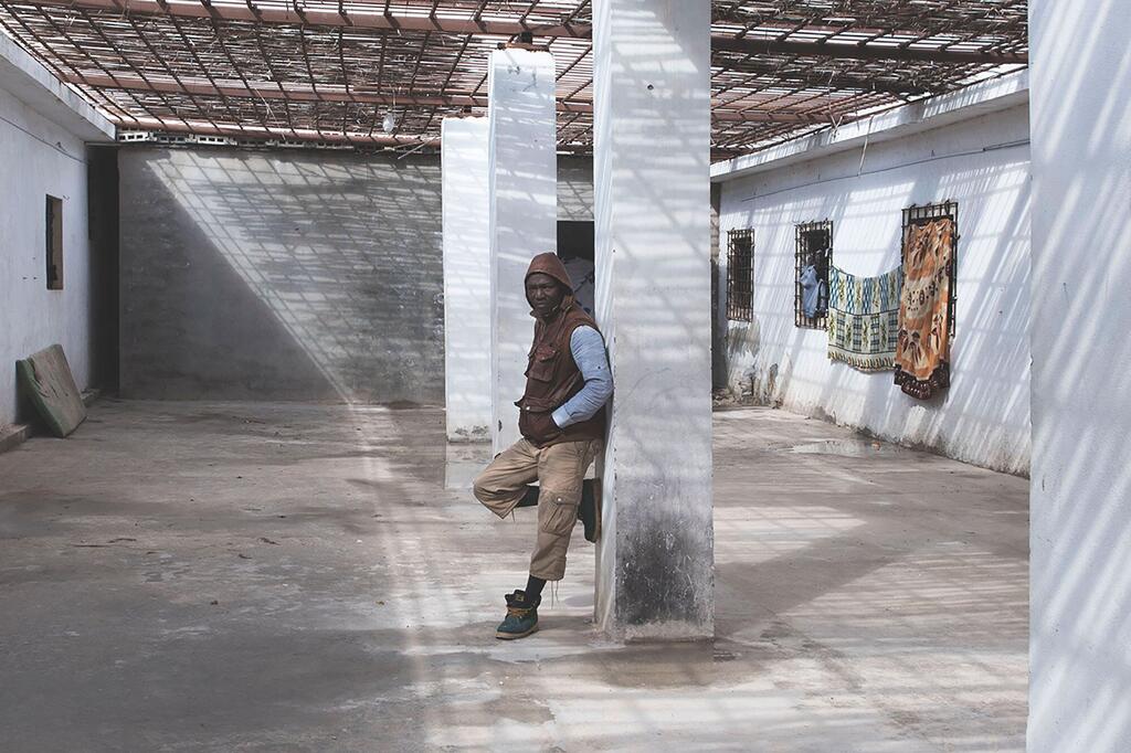 Un migrant s'appuie sur un pilier dans la cour d'un centre de détention à Al Khoms, en Libye, soulignant les conditions difficiles auxquelles sont confrontés les réfugiés et les migrants dans la région.