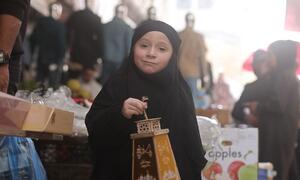 A young girl in Gaza holds a decorated Ramadan lantern, smiling as she participates in the festive celebration.