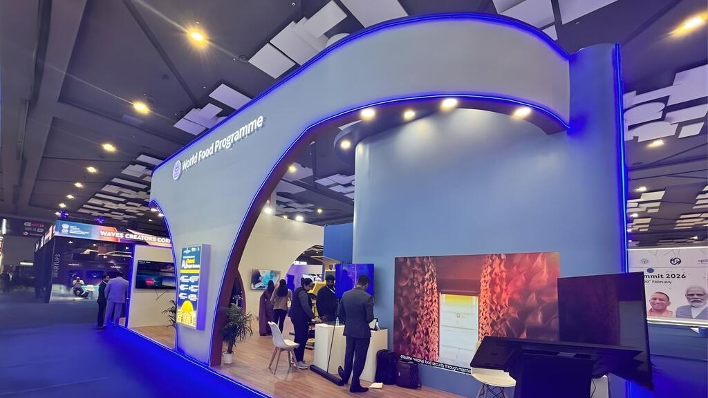 Kituo cha Mpango wa Chakula Ulimwenguni katika Mkutano wa AI 2024 huko India, India, ikionyesha arches ya kisasa ya bluu, maonyesho ya dijiti, na wahudhuriaji wakichunguza maonyesho.