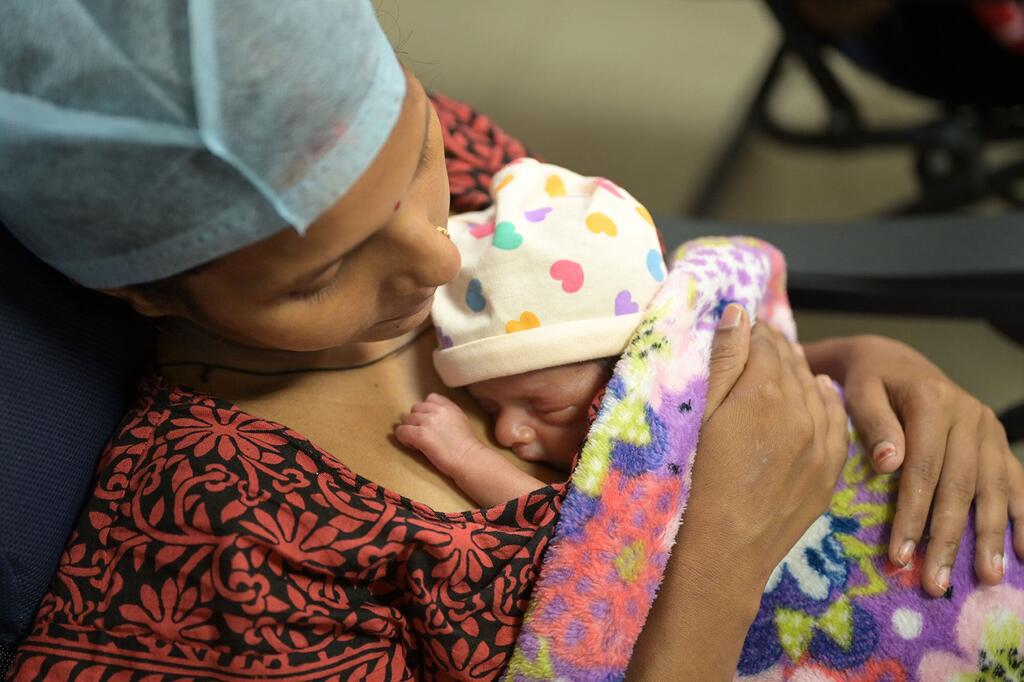 Une mère nommée Mahima fournit des soins maternels Kangaroo à son nouveau-né prématuré au SNCU de Lucknow, Uttar Pradesh, Inde, le 18 octobre 2024. Le bébé, portant un chapeau coloré, repose peau à peau contre la poitrine de la mère, enveloppé dans une couverture. Cette image souligne le rôle vital de l'action communautaire et le soutien de l'UNICEF en Inde dans la construction d'un avenir plus sain pour tous.