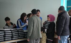 WFP distributes food aid to displaced families sheltering in a public school in Tariq Jdide, Beirut, Lebanon. Volunteers hand out stacks of food boxes to adults and children.