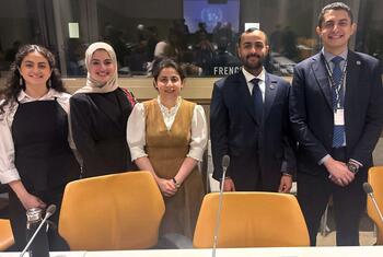 خمسة شباب مصريين، ثلاثة نساء ورجلان، يظهرون في صورة خلال مؤتمر للأمم المتحدة. يرتدون ملابس رسمية، بما في ذلك بدلات وحجاب، ويقفون خلف طاولة مزودة بميكروفونات.