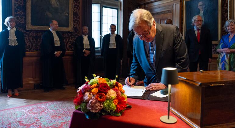 安东尼奥·古特雷斯在国际法院为其成立 80 周年签署纪念册，周围是身着法袍的法官。